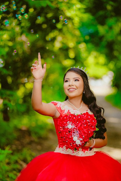 smiling quinceañera in a red dress in the forest