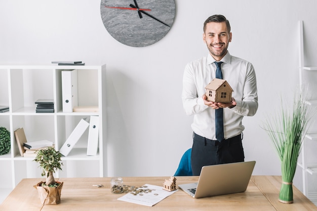 Smiling real estate agent holding house