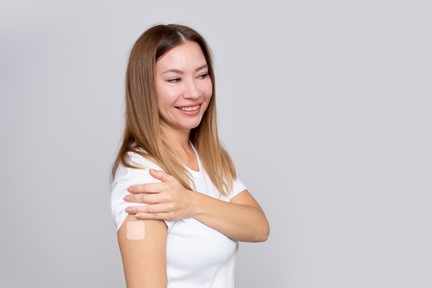 Smiling real middle age woman  with a plaster or patch on her hand  receiving a vaccination