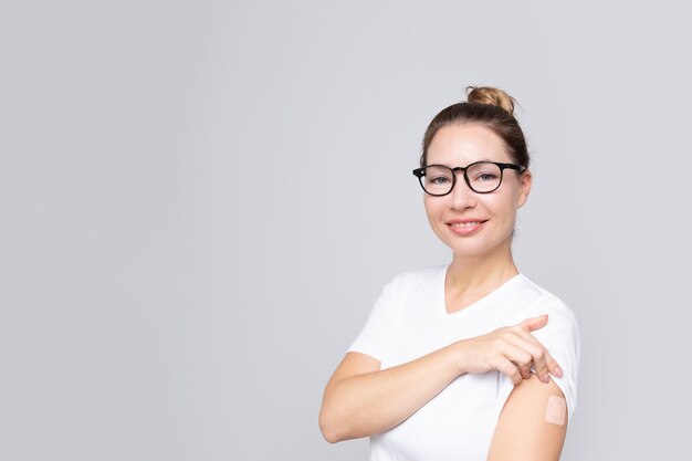 Smiling real middle age woman  with a plaster or patch on her hand  receiving a vaccination