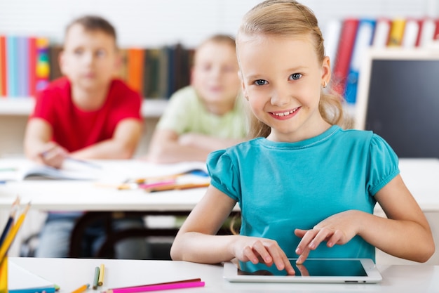 Smiling School Girl in the Classroom Using Tablet