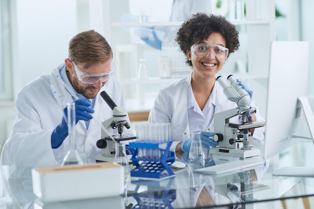 Smiling scientists looking at camera arms crossed in laboratory