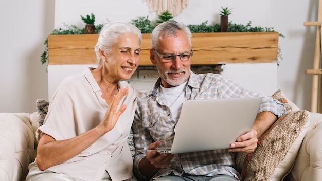 Smiling senior couple doing video chatting on laptop