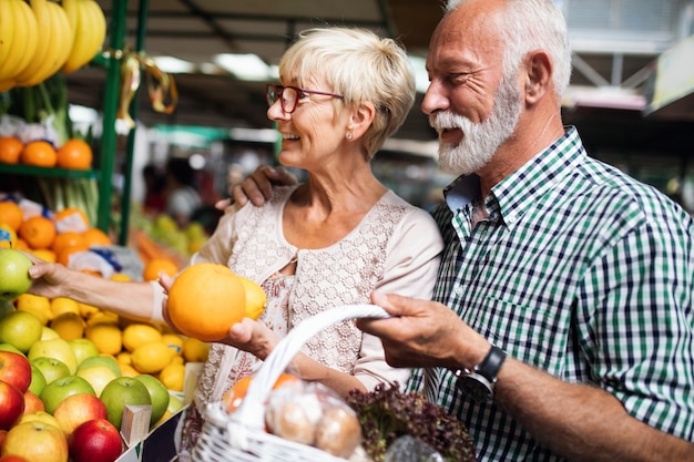 Smiling senior couple holding basket with vegetables at the grocery shop