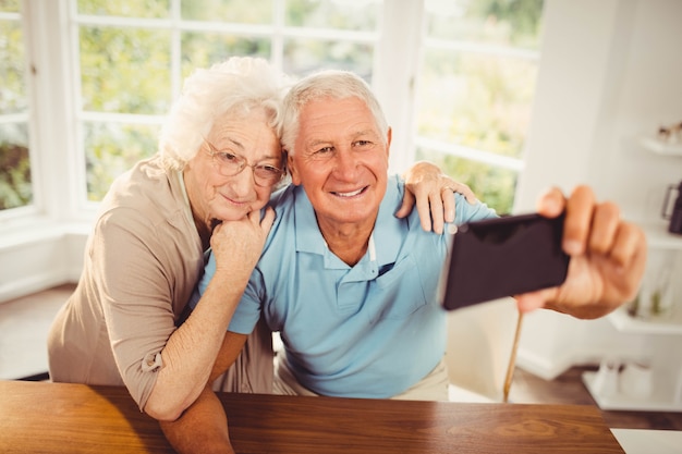 Smiling senior couple taking selfie at home