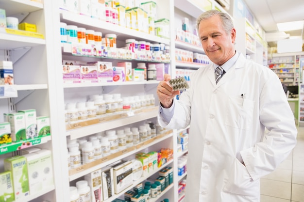 Smiling senior pharmacist holding blister