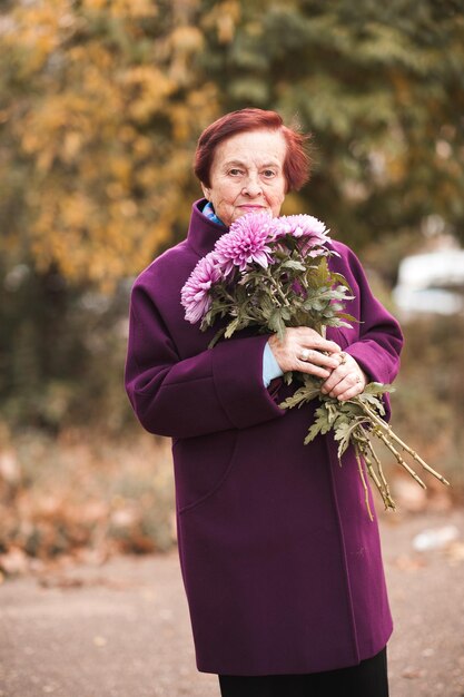 Smiling senior woman holding flowers outdoor