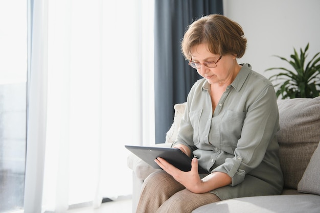 Smiling senior woman at home connected on internet