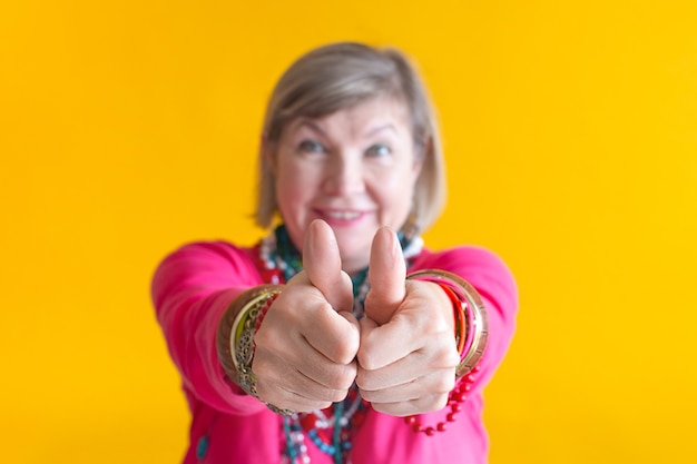 Smiling senior woman showing class sign with hands having fun in stylish clothes