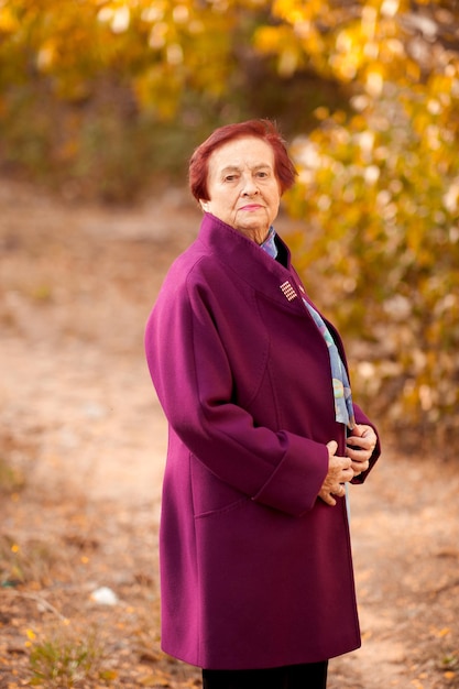 Smiling senior woman wearing stylish winter coat posing in park