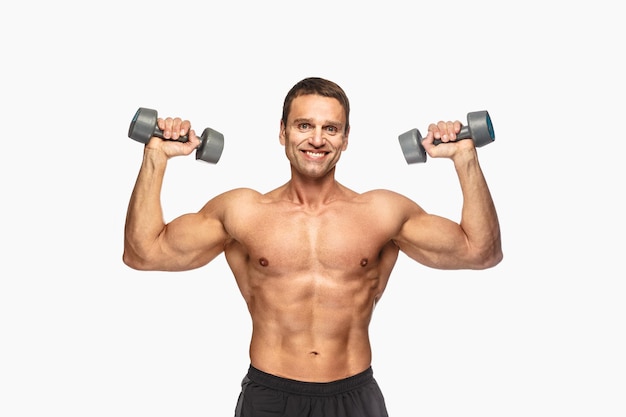 Smiling shirtless male with dumbbells isolated on white background.