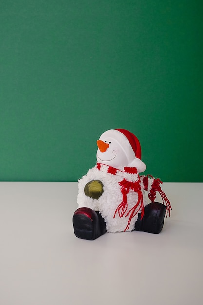 Smiling snowman toy dressed in scarf and cap sitting