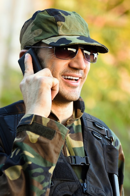 The smiling soldier in uniform is talking at phone