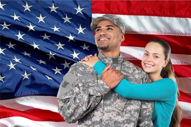 Smiling soldier with his wife standing against  american flag background