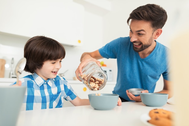 Smiling Son and Father Have Breakfast in Kitchen.