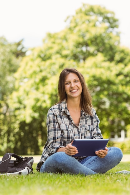 Smiling student sitting and using tablet pc