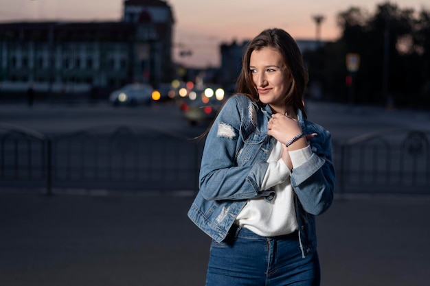 Smiling stylish young woman walk in city street summer time Young pretty girl on evening city background