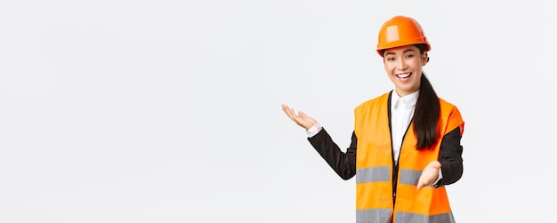 Smiling successful female asian construction manager architect introduce her project pointing hand at blueprint explain her building plan Industrial woman giving speech to investors