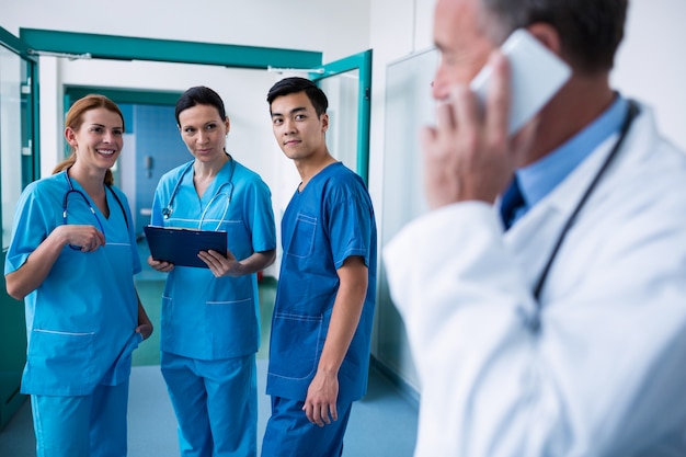 Smiling surgeons standing together with clipboard in corridor