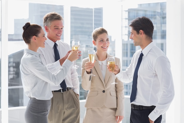 Smiling team of business people clinking their flutes of champagne