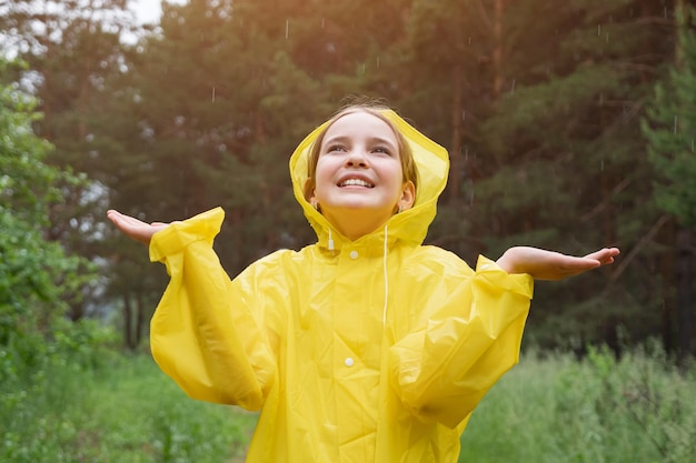 Smiling teen girl enjoys standing in green rainy forest