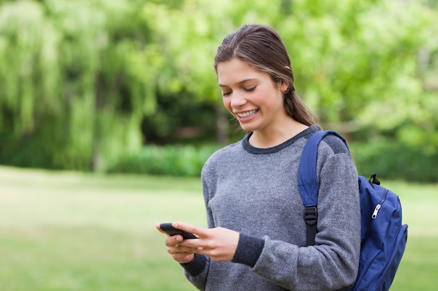 Smiling teenage girl using her cellphone while receiving a text