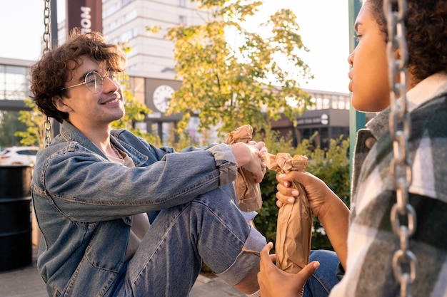 Smiling teenager with bottle looking at his girlfriend