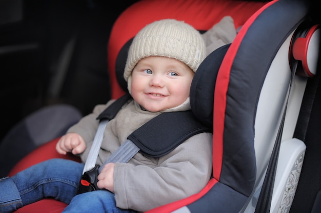 Smiling toddler boy sitting in car seat