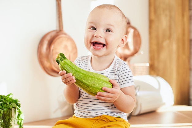 Smiling toddler boy with a zucchini in his hands