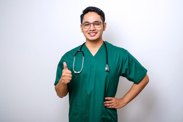 Smiling upbeat confident male asian nurse in scrubs have all under control show thumbsup in approval guarantee quality of service in clinic