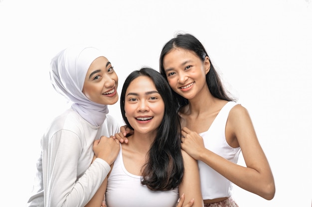 Smiling a veiled girl and two asian young girl stand next to each other