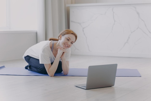 Smiling white woman has remote personal training and talking in front of computer