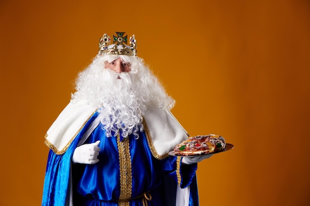 Smiling Wise Man holding a quotroscon de reyesquot in his hand on an orange background