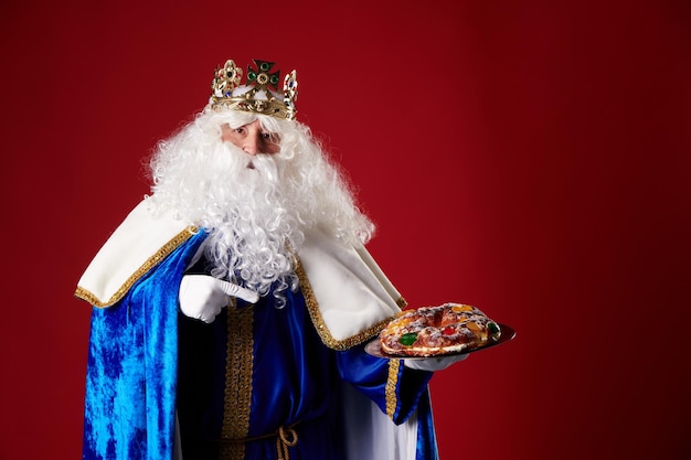 Smiling Wise Man holding a quotroscon de reyesquot in his hand on a red background