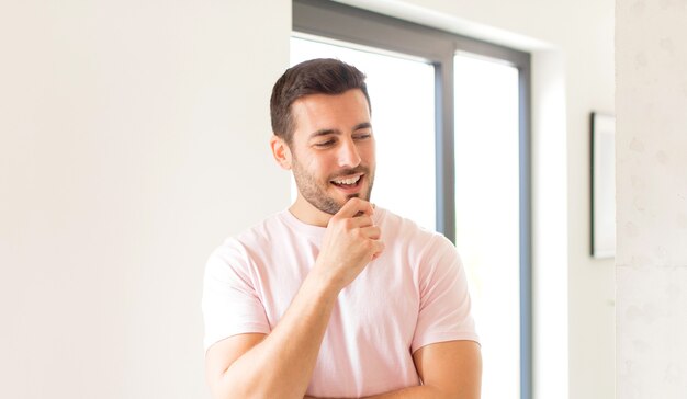 smiling with a happy, confident expression with hand on chin, wondering and looking to the side