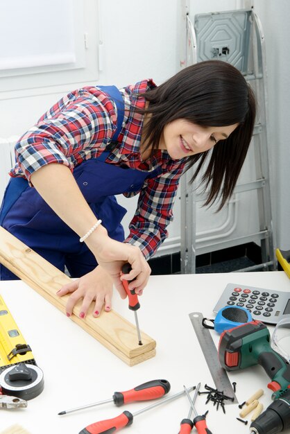 Smiling woman assembling wooden planks using screwdriver