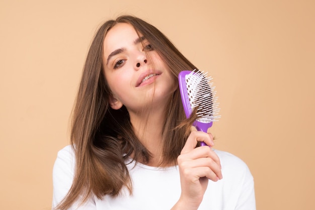 Smiling woman brushing hair with comb beautiful girl combing long hair with hairbrush