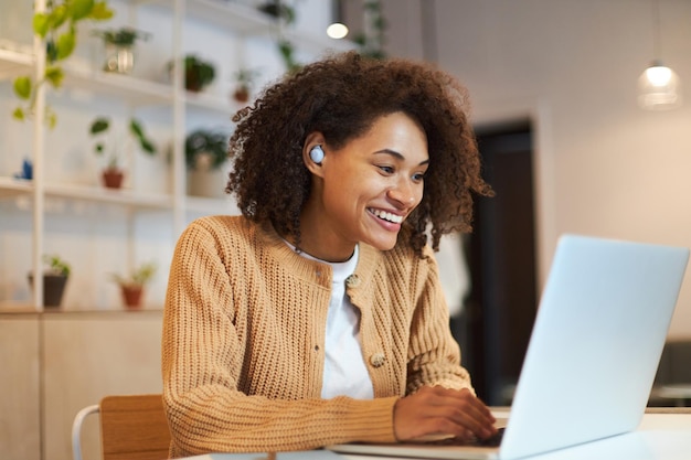 Smiling woman call center worker with earphones having online conference by video link on laptop