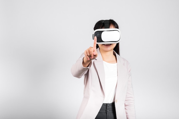 Smiling woman confidence wearing VR headset device touching air during virtual reality experience isolated white background, Asian happy portrait female playing video game studio shot, copy space