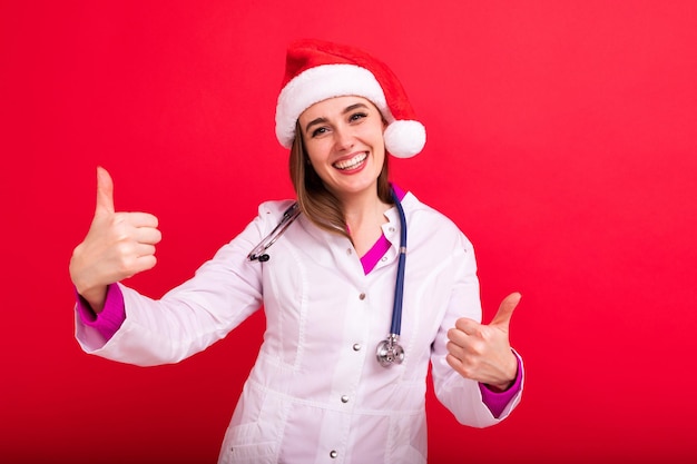 A smiling woman doctor in a white coat in a Santa Claus hat shows the class and looks into the camera