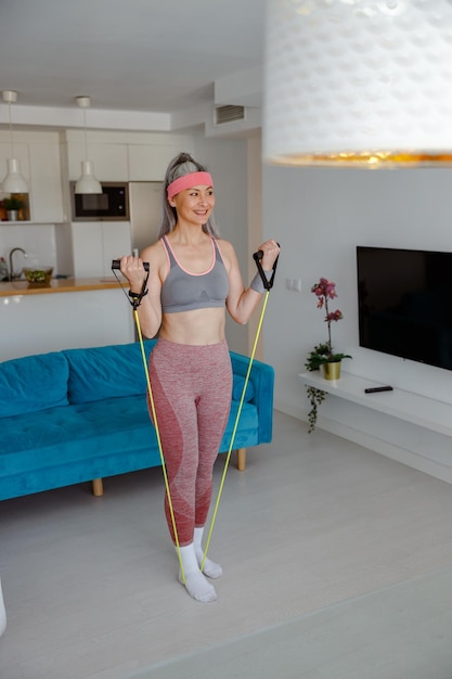 Smiling woman doing exercise with elastic fitness rope