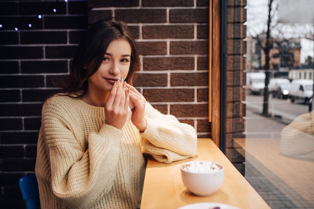 Smiling woman dressed warm sweater, drink marshmallow with milk coffee cacao or latte