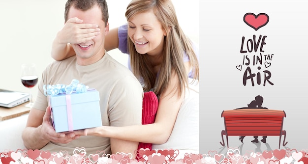 Smiling woman giving a present to her boyfriend against love is in the air