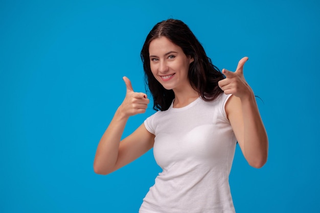 Smiling woman giving thumbs up on blue background