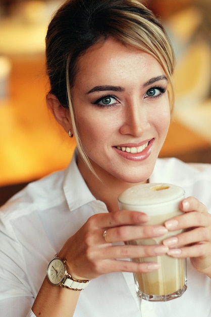 Smiling woman in a good mood with cup of coffee sitting in cafe