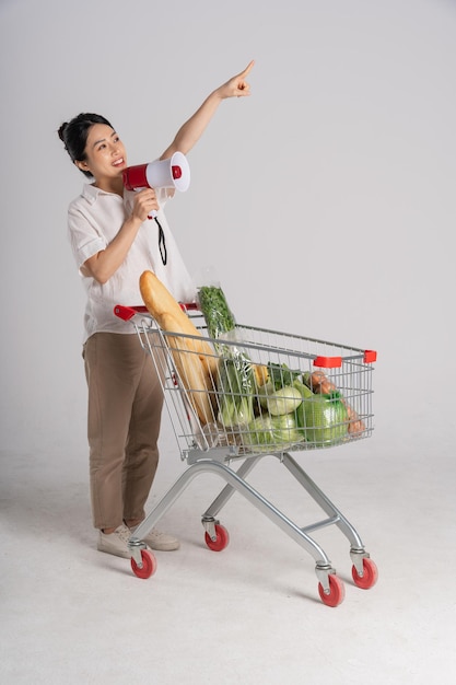 Smiling woman happily pushing a supermarket cart isolated on white background