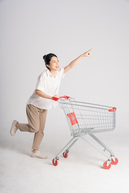 Smiling woman happily pushing a supermarket cart isolated on white background