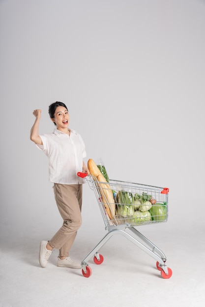 Smiling woman happily pushing a supermarket cart isolated on white background