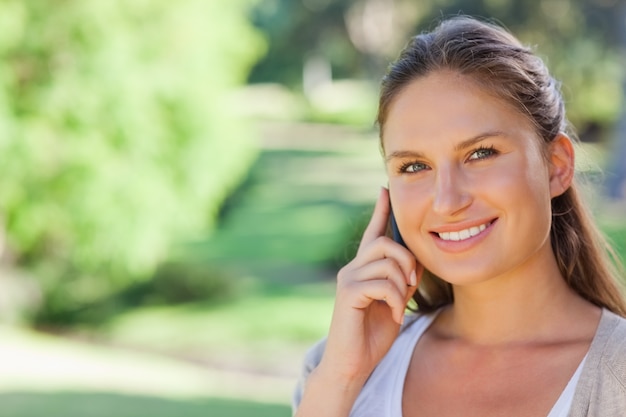 Smiling woman on her phone in the park