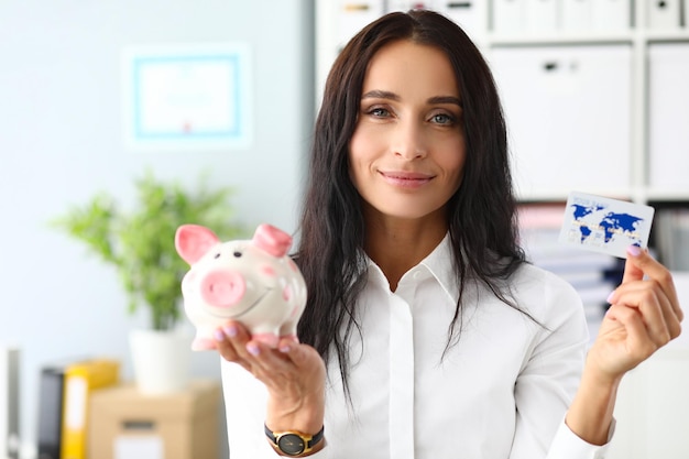 Smiling woman holding piggy bank and bank card